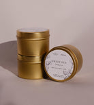Three gold Sweet Pea travel tins, one tipped forward to show its lid label with a drawing of the sweet pea.