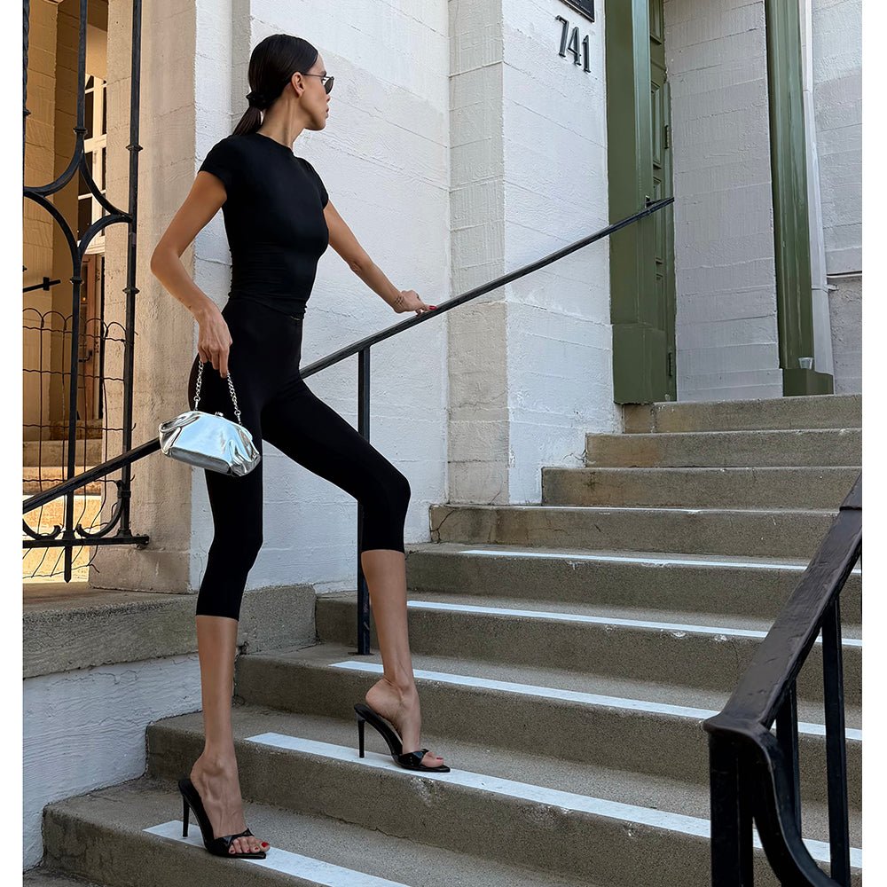 Woman in black climbing stone steps, the silver clutch in her hand