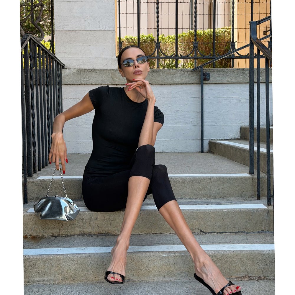 Woman in black sitting on stone steps, the silver clutch hanging from her hand on its chain