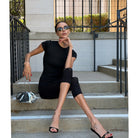 Woman in black sitting on stone steps, the silver clutch hanging from her hand on its chain