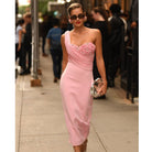Woman in a pink dress walking along a city footpath, the silver clutch in her hand