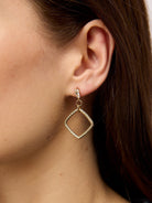 Close view of an ear wearing a gold-tone textured square drop earring