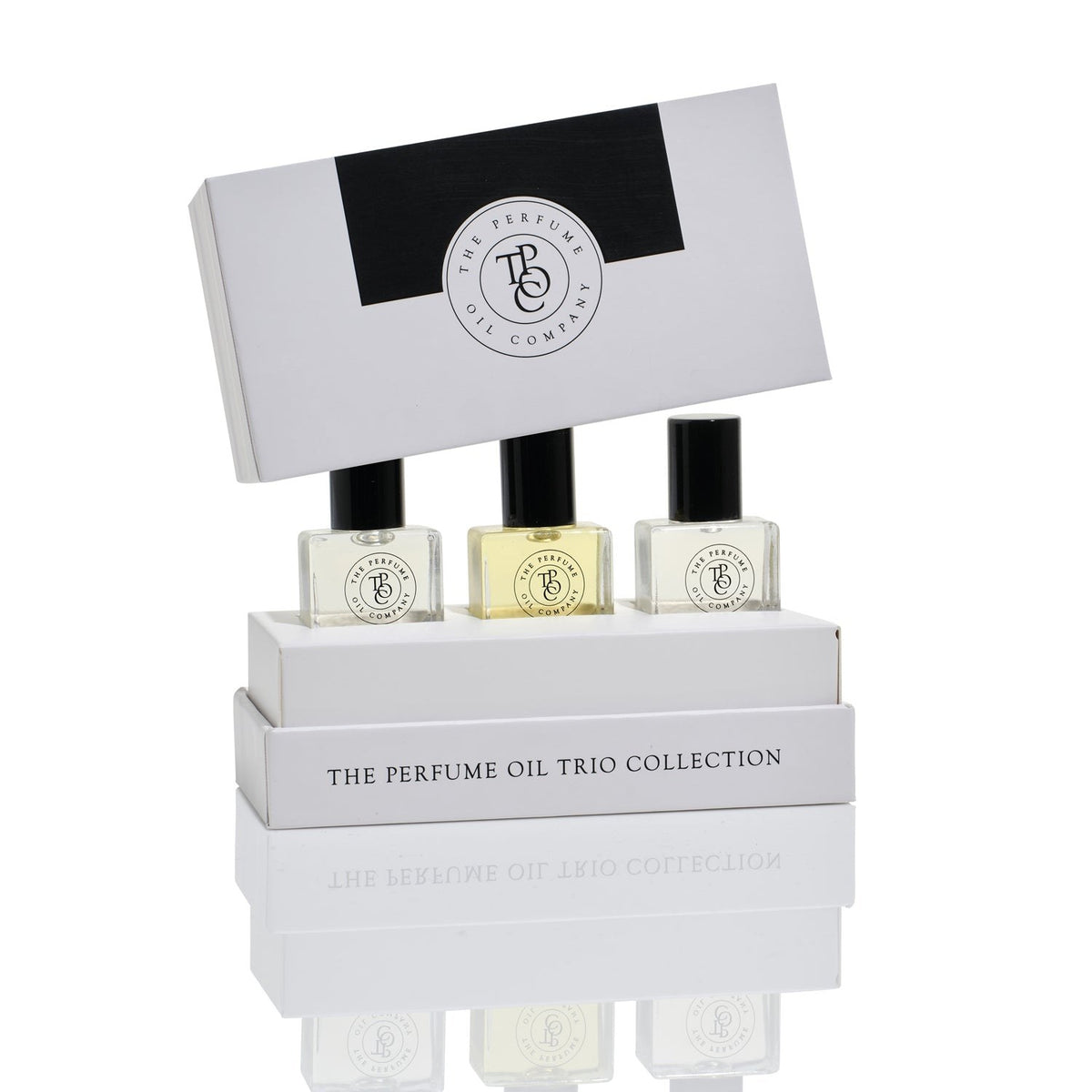 The grey trio box with its lid lifted over the three perfume oil bottles.