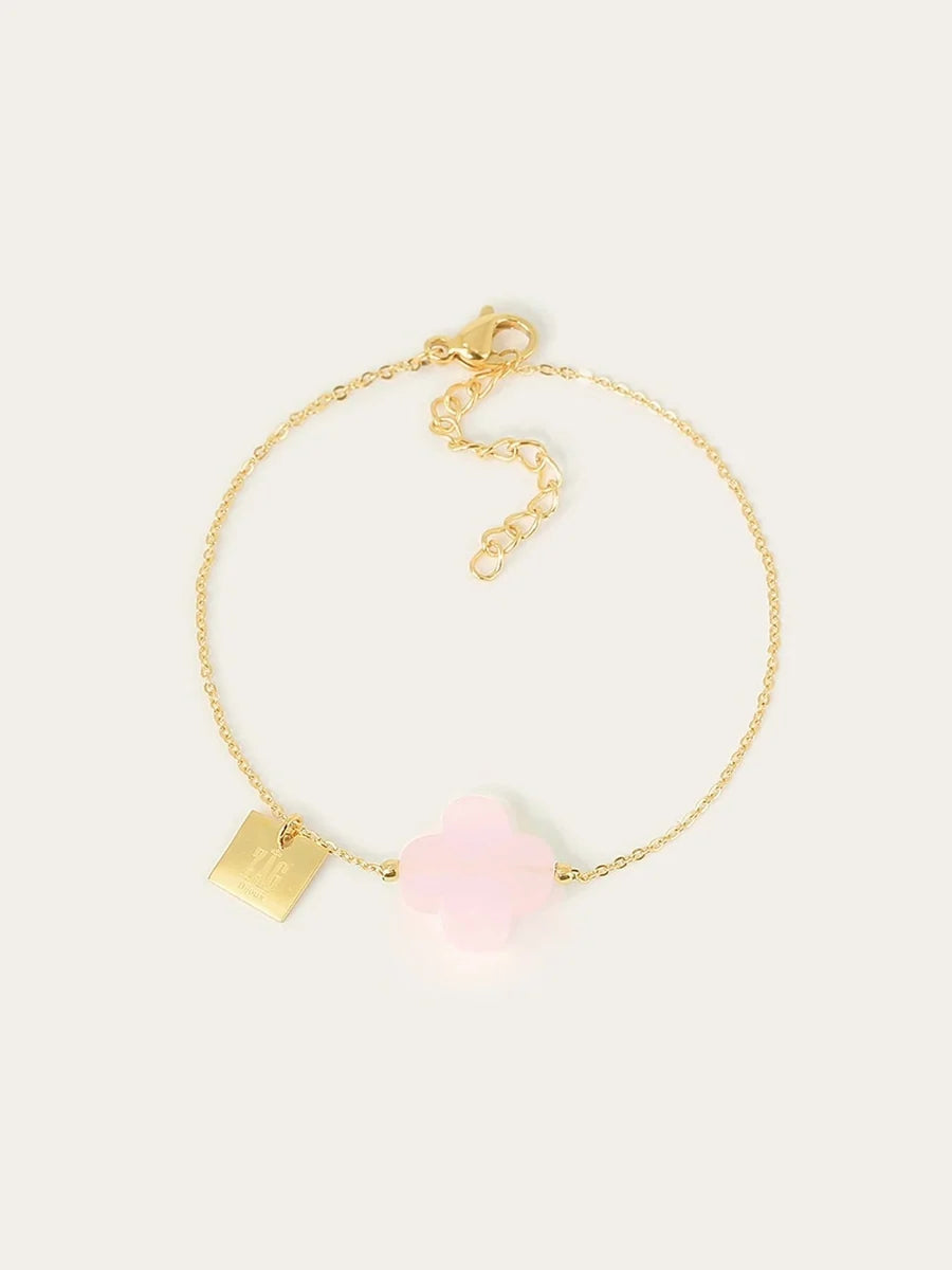 Fine gold chain bracelet with a pale pink rose quartz four-leaf clover and a small square gold tag.