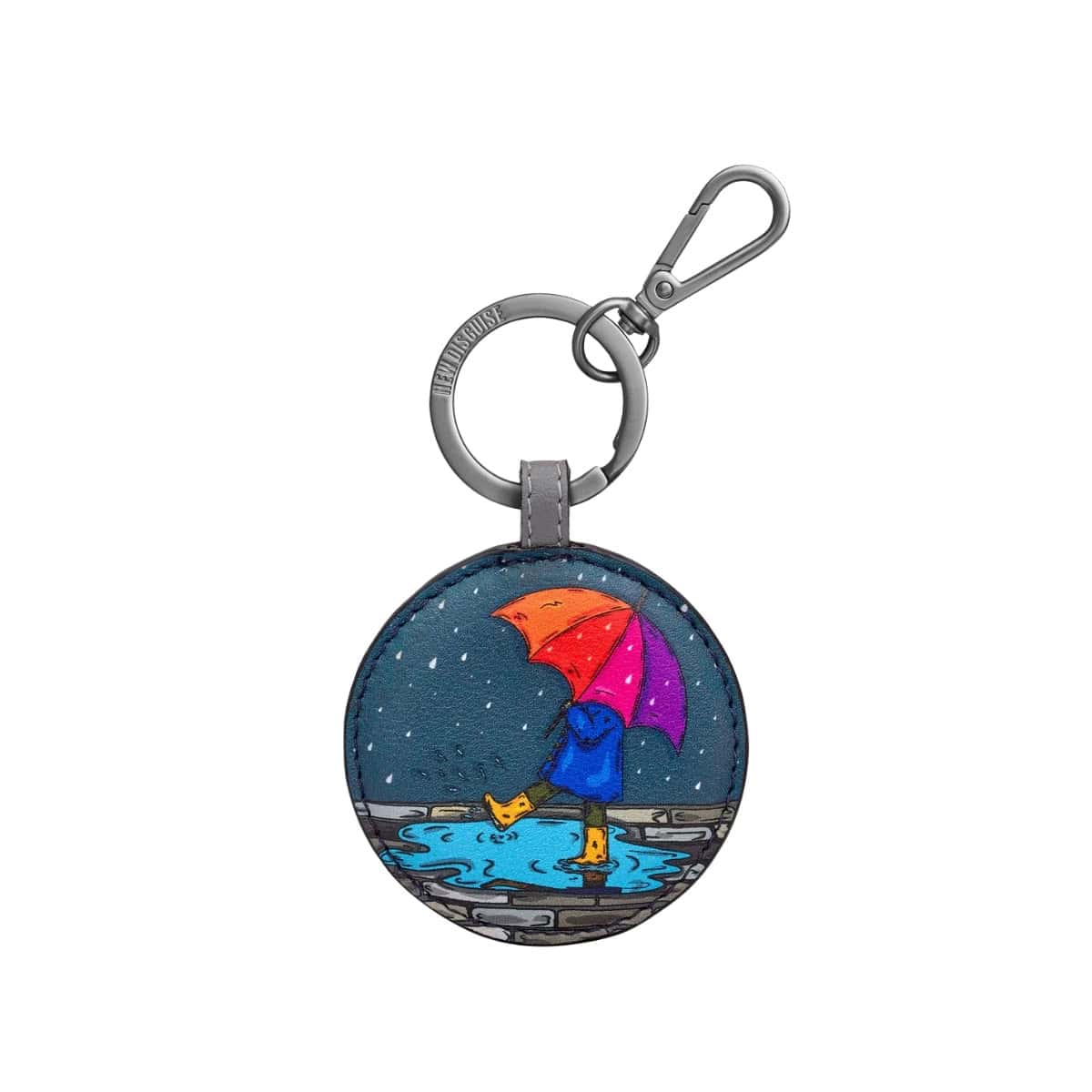 Round Rainy Day keyring: a figure in a blue raincoat and yellow boots under an orange, pink and purple umbrella, splashing in a puddle on slate blue.