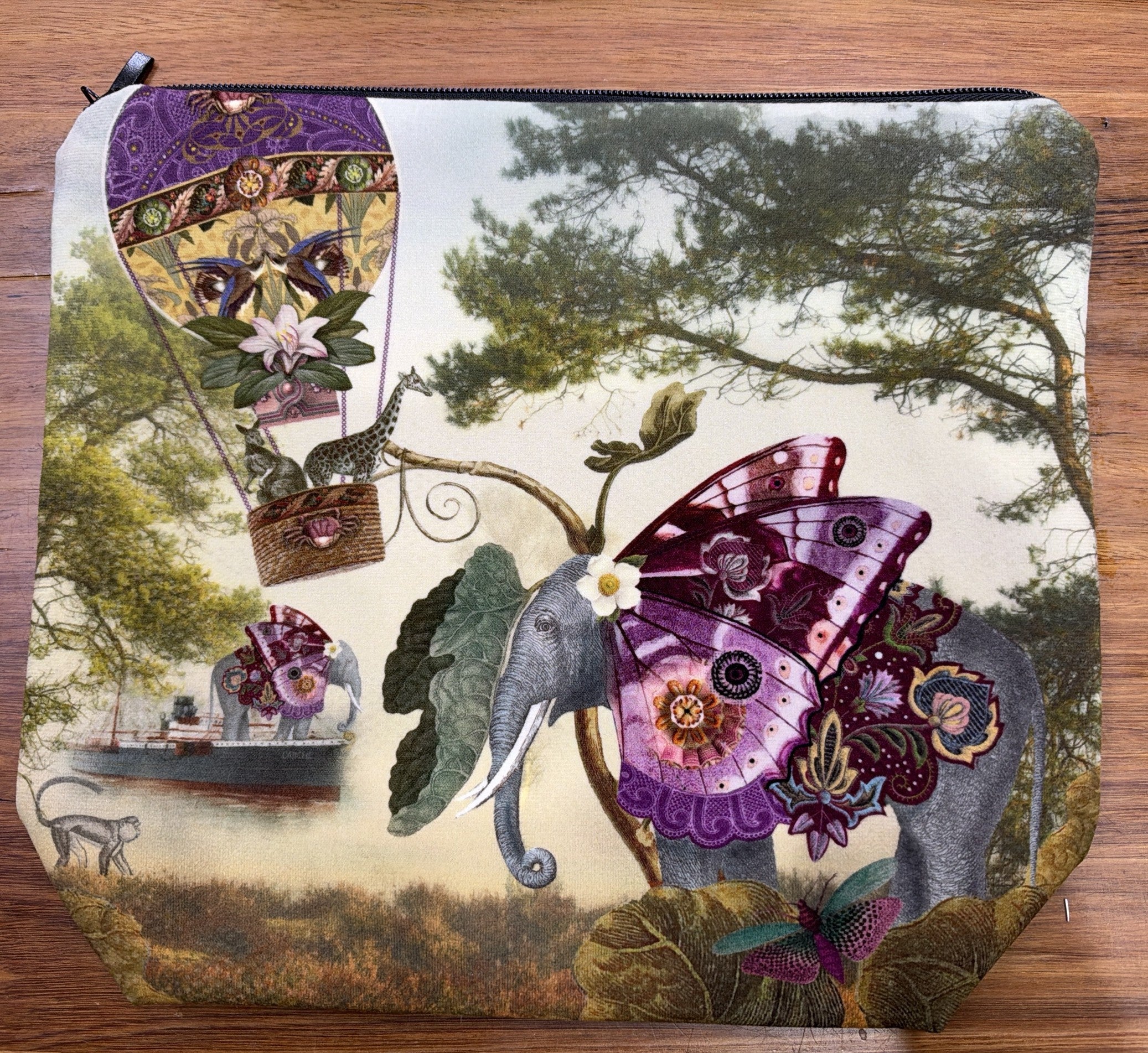 Velour cosmetic bag printed with Isabelle Frioux's Butterfly Elephant: an elephant with purple butterfly wings beside a hot-air balloon, with a black zip.