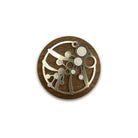 The round wattle brooch close up on white, silver steel wattle cut-outs on walnut timber.