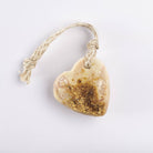 A cream heart soap topped with dried petals, with a jute loop