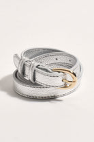 Thin metallic silver belt coiled up, showing its rounded gold-tone buckle