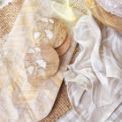 Bindi tea towel styled with mango wood serving boards and coasters on a woven mat