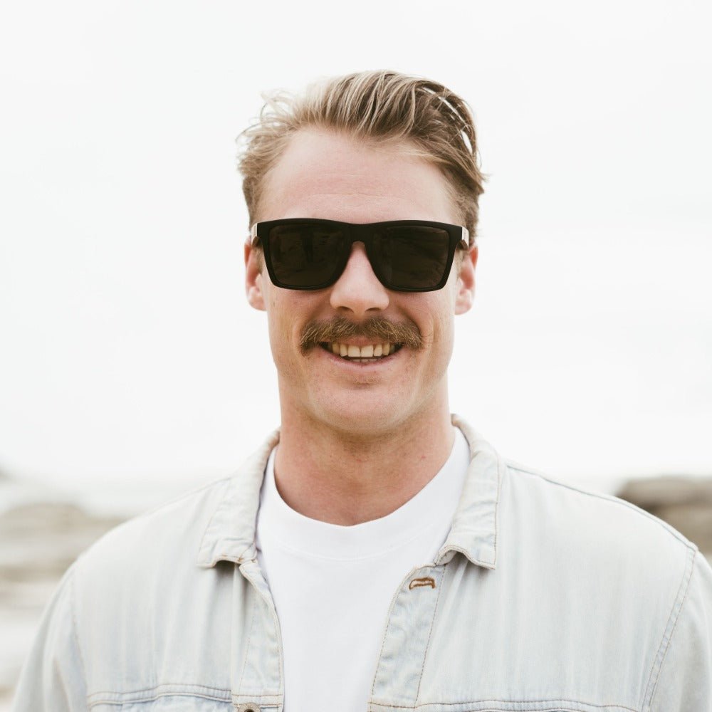 A man with a moustache wearing the Dalton sunglasses outdoors, front on