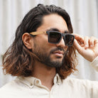 A man with long dark hair adjusting the Dalton sunglasses as he wears them