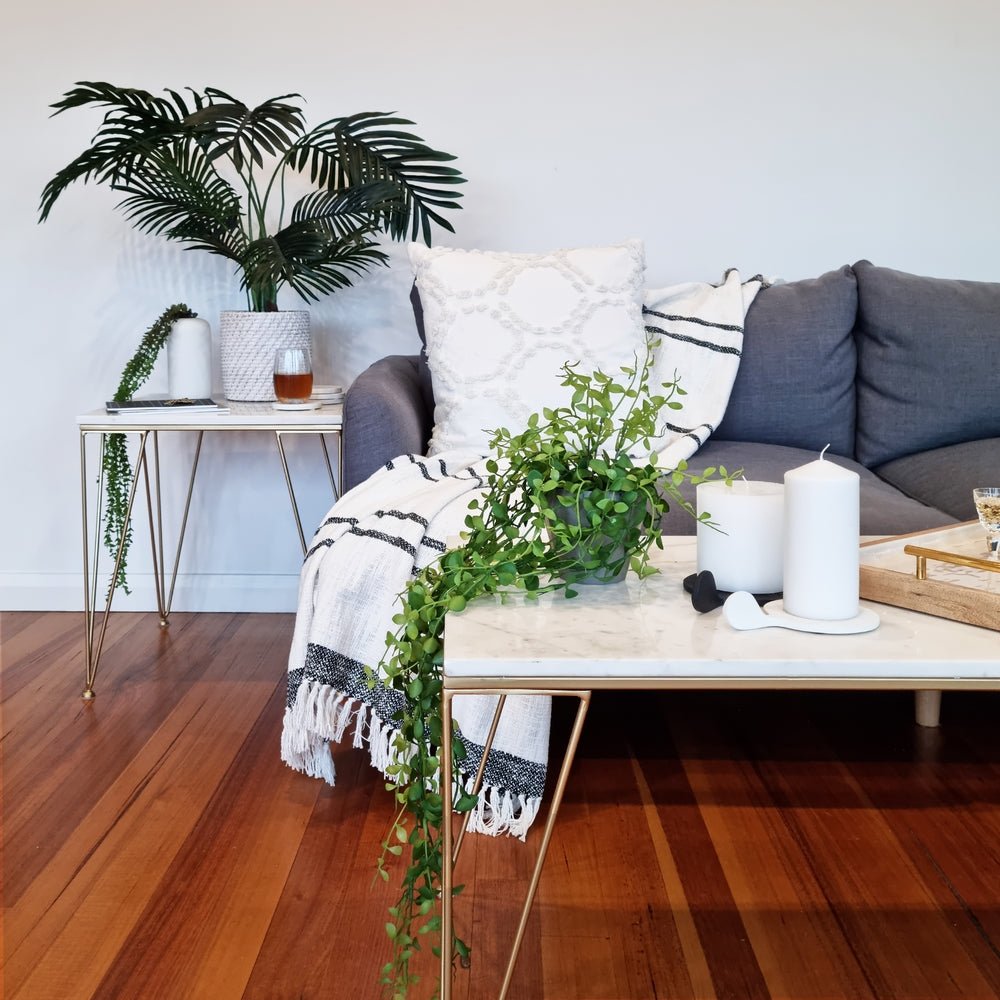 Black Ostra candle holder holding a white pillar candle on a coffee table in a lounge room