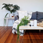 Black Ostra candle holder holding a white pillar candle on a coffee table in a lounge room