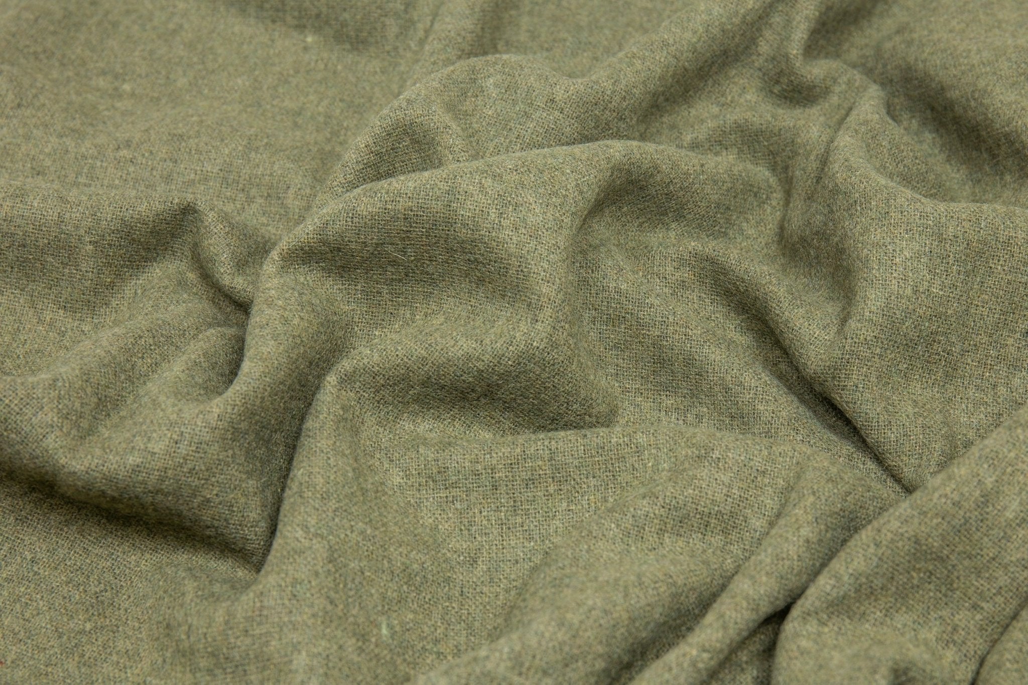 Close-up of the olive throw's soft draped weave showing its flecked wool texture