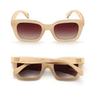 Two pairs of Zahra sunglasses in nude, one front-on and one folded, showing the pale wood arms