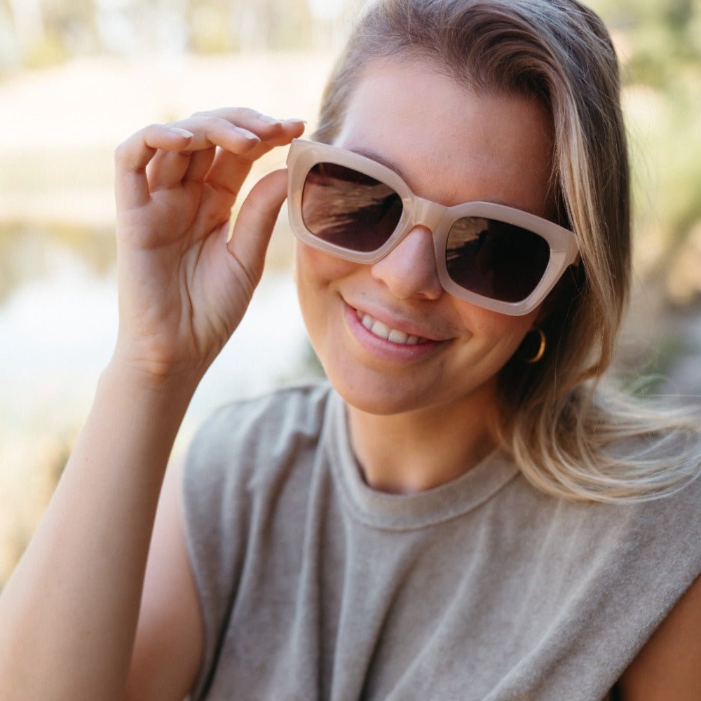 A woman with blonde hair adjusting the Zahra sunglasses
