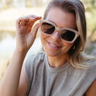 A woman with blonde hair adjusting the Zahra sunglasses